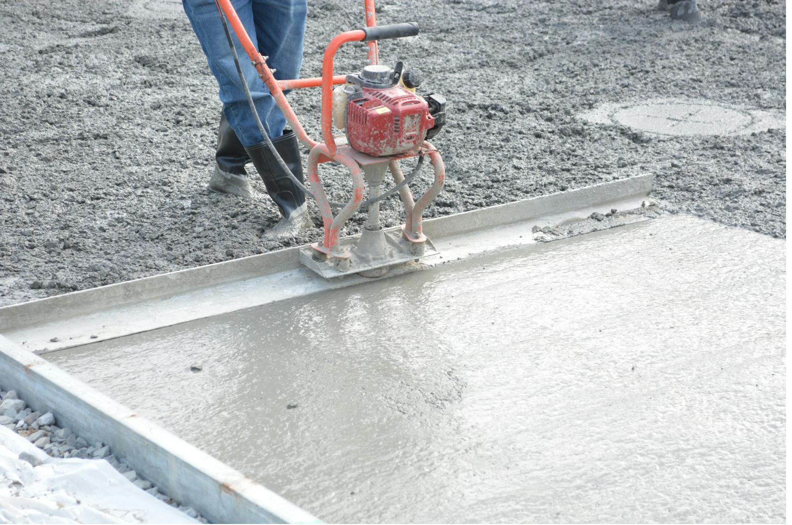 Concrete contractor finishing fresh slab with screed in Renton WA